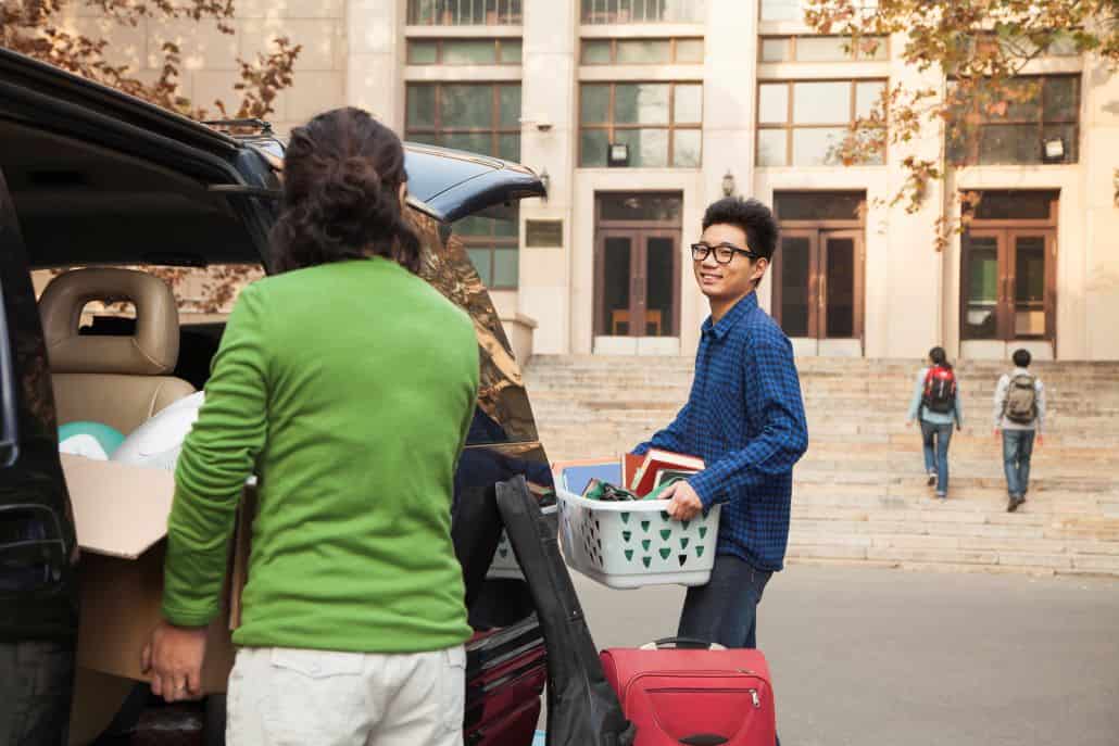 Young man with parents unloading car at college campus