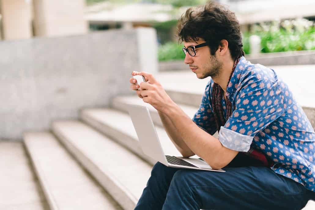 Young man looking at phone while sitting on steps