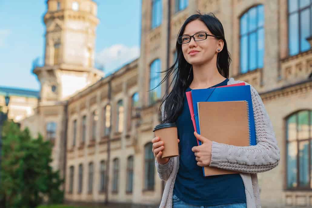 Student with books and coffee in hand