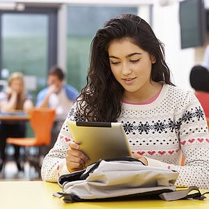 Female Teenage Student In Classroom With Digital Tablet